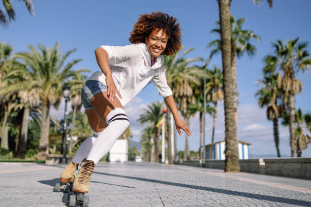 istock Black woman on roller skates rollerblading in beach promenade with palm trees 907495620
