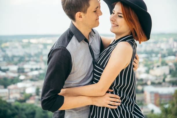 istock couple standing on the hill hugging and looking on city view 907503882