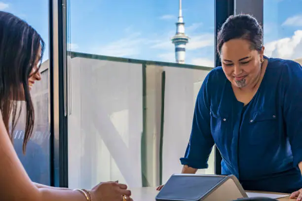 Maori businesswoman making a conference call in an office with the Auckland Skytower behind her in the background