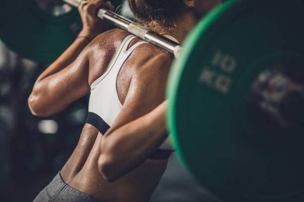 istock Unrecognizable sweaty woman doing back exercises with barbell. 907505190