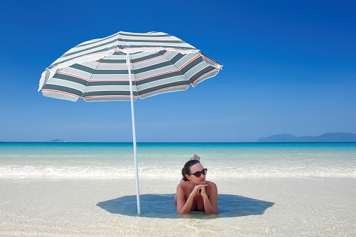 Woman on a desert tropical beach relax in the sunny day under a umbrella. Travel background .