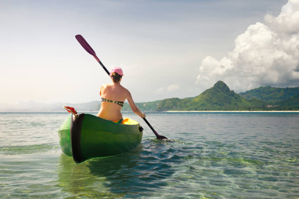 istock Woman traveler exploring calm tropical beach by canoe. 907524344
