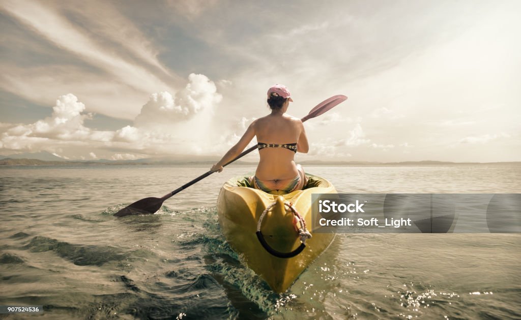 Woman traveler exploring calm tropical bay by kayak. Woman in bikini exploring calm tropical beach by canoe. Kayaking Stock Photo