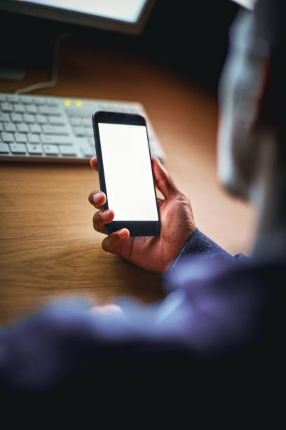 istock Male hands with mobile phone, computer in the background 907538396