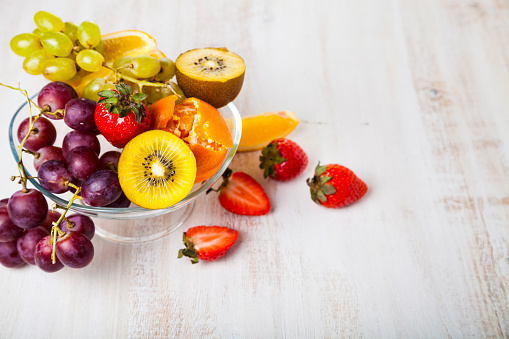 Ripe fruits on a transparent plate on a wooden background. Healthy eating.