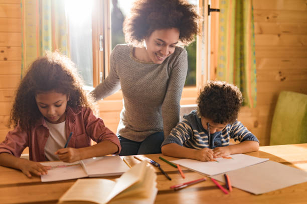istock Young black mother assisting her small children in drawing at home. 907545962