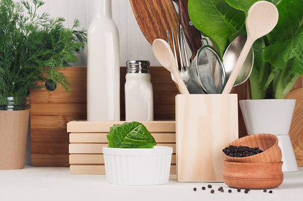 istock White modern kitchen decor with beige rustic wooden utensils, fresh green spinach, dill in pot on wood background. 907549668