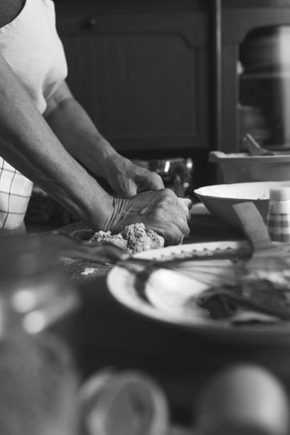 istock Senior female baker kneading dough in kitchen. 907549702