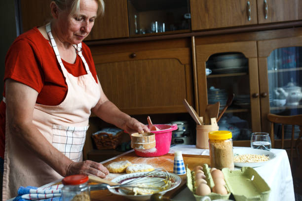istock Senior female baker kneading dough in kitchen. 907549704