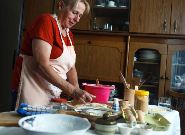 istock Senior female baker kneading dough in kitchen. 907552156