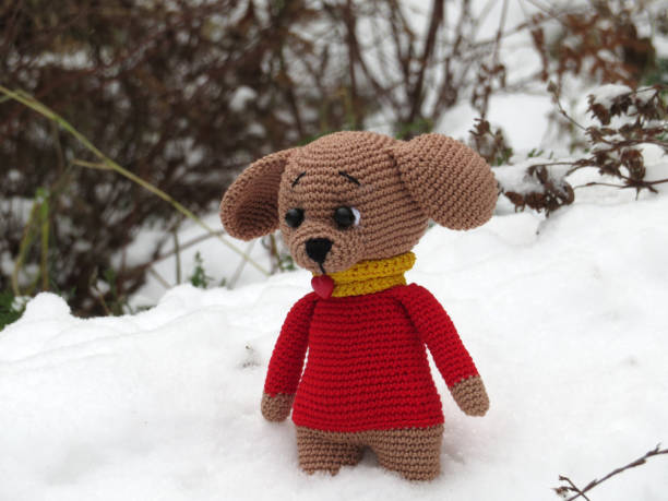 istock Lonely knitted toy dog in winter park 907553292