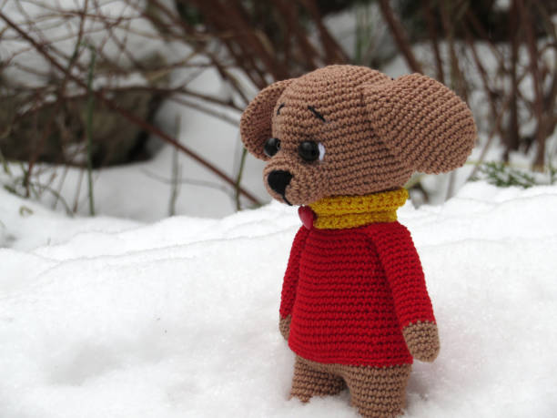 istock Knitted toy dog on the snow 907554332
