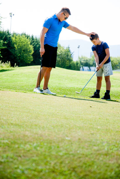 istock Golfer Showing a Kid the Right Pose for Teeing Off the Golf Ball by Using his Hand 907563684