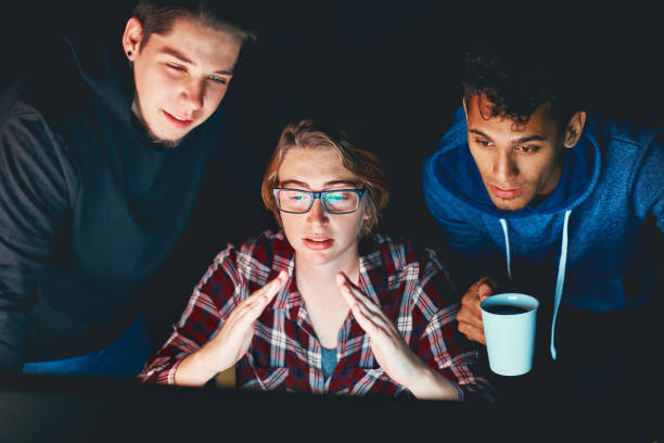istock Three young adults gathered round nighttime computer monitor 907564662