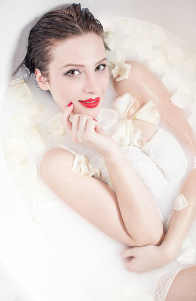 istock Woman relaxing in a milk bath with rose petals 907570992