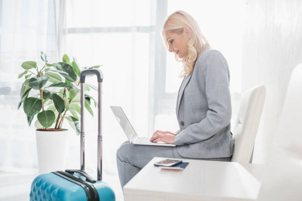 istock businesswoman with luggage using laptop 907571112