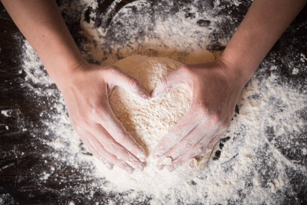 istock Woomens hands holding a finished clean dough in heart shape 907574452