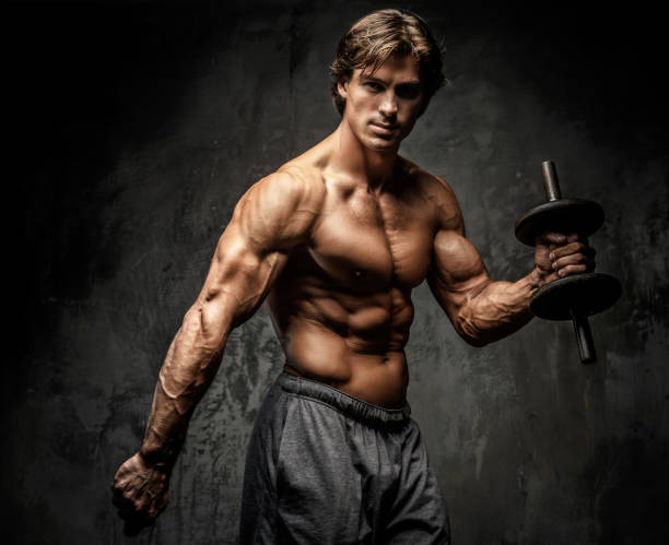 istock Shirtless bodybuilder holding dumbell. 907577944