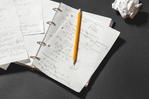 Mathematical equations written in a notebook. Solving a mathematical problem in a notebook. Crumpled piece of paper on black desk. homework paper stock pictures, royalty-free photos & images