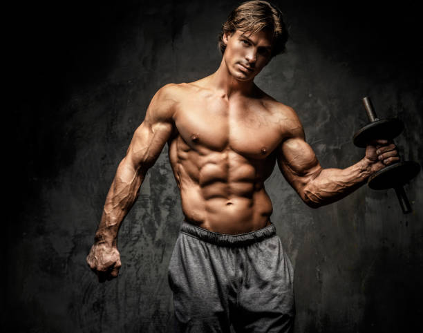 istock Shirtless bodybuilder holding dumbell. 907579008