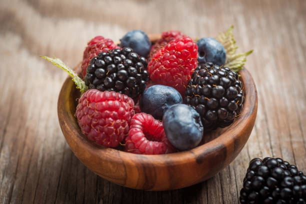 istock Blueberries and raspberries bowl on wooden table 907579918