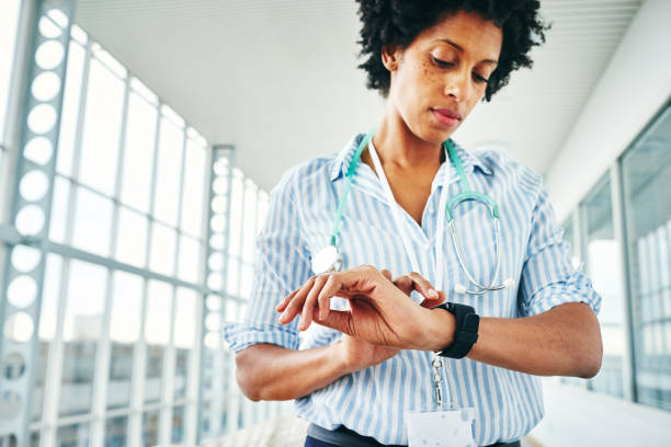 Female physician checking her digital wrist watch stock photo