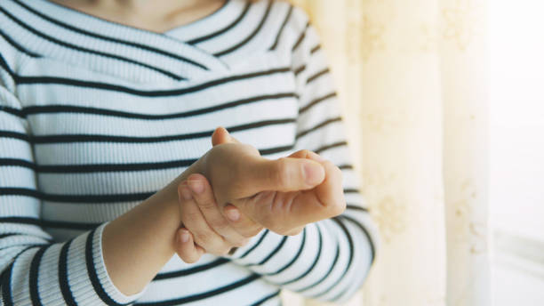 donna che massaggia la mano e il polso artritici - wrist foto e immagini stock