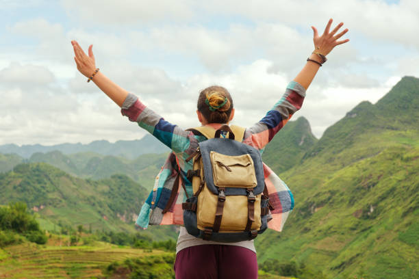 istock joyful traveler jumping with raised hands enjoying view at mountains 907593956
