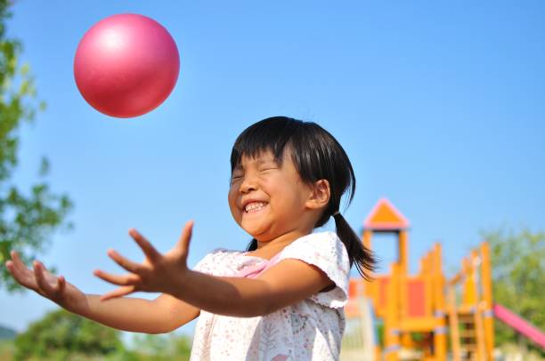 niña jugando con pelota - lanzar actividad física fotografías e imágenes de stock