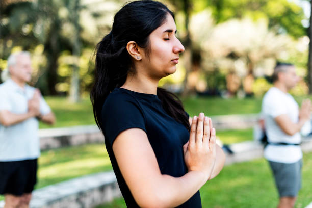 istock Group of people doing yoga at the park 907599218