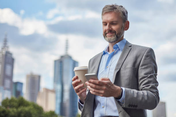 istock Smiling businessman using mobile phone in city 907610462
