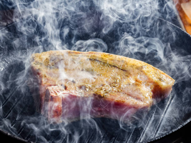 istock smoke and steam rise from a pork steak 907610596
