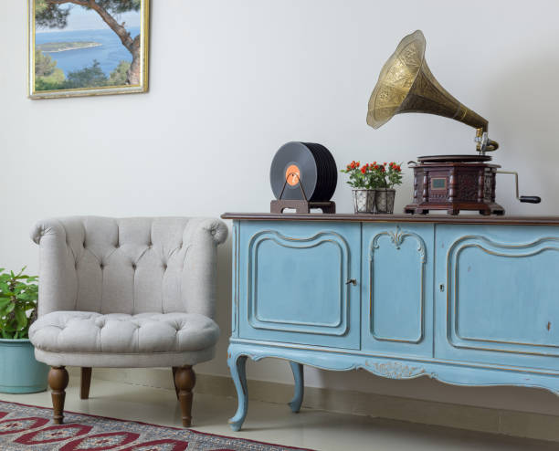 retro aus weißen sessel, vintage leichte blaue anrichte aus holz, alte plattenspieler (gramophone) und vinyl-schallplatten auf hintergrund beige wand, porzellan gefliesten boden und roten teppich - sideboard stock-fotos und bilder