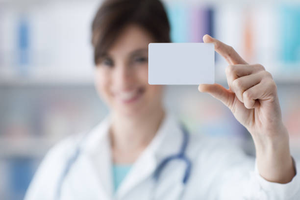 médico sostiene una tarjeta de negocios - smiling business card horizontal women fotografías e imágenes de stock