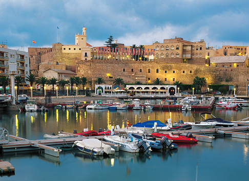 Sunset view of Sailing boats moored at the harbor of Melilla with the Old city Fortress at the back.