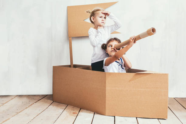 two children little girls home in a cardboard ship play captains and sailors - bebês meninas imagens e fotografias de stock