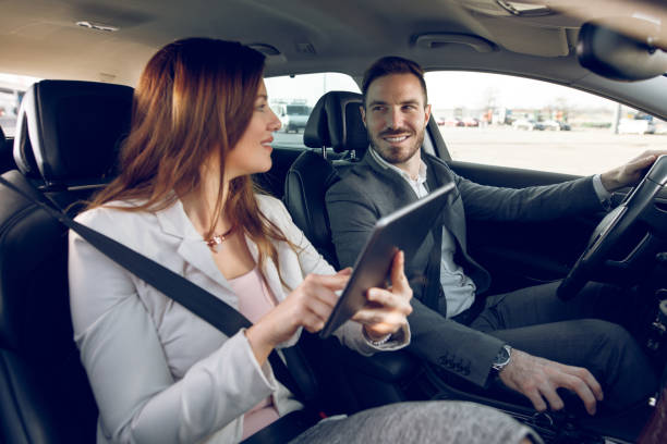 istock Businesswoman using digital tablet while businessman driving a car 907633030