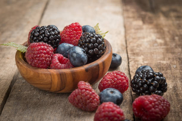 istock Blueberries and raspberries bowl on wooden table 907634172