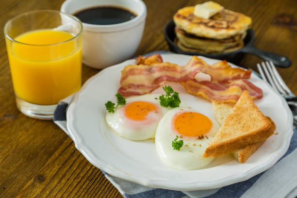 istock American breakfast with sunny side up eggs, bacon, toast, pancakes, coffee and juice 907634368