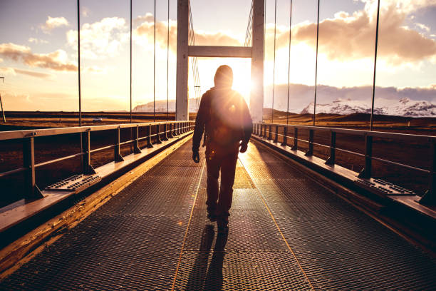 Solo traveler walking on a bridge with arm raised