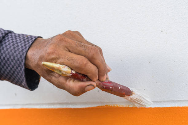 istock Hand painting white wall with orange color 907639540