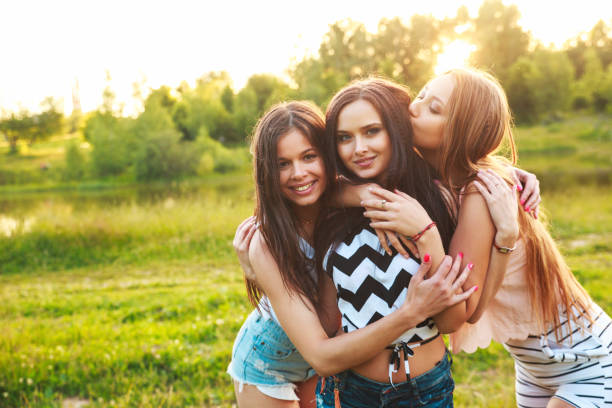 istock three women hugging each other outdoors and laughing on sunset. 907640044