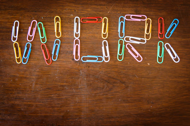 bored at the office knolling concept: single word 'work' made with paper clips on desk - escaping the rat race imagens e fotografias de stock