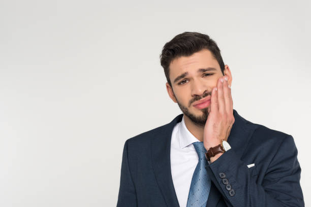 istock young businessman with toothache looking at camera isolated on grey 907645882