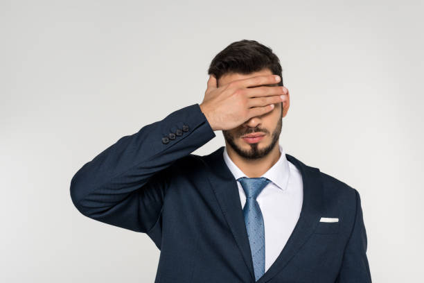 istock young businessman closing eyes with palm isolated on grey 907646046