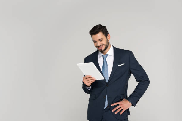 istock smiling young businessman holding digital tablet isolated on grey 907646280