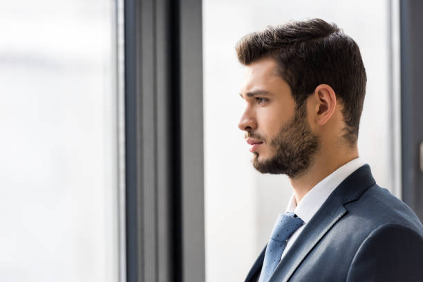 istock side view of handsome young businessman looking at window 907648960