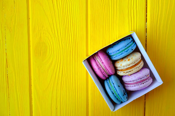 French multi tastes macarons buiscits whith flowers on wooden background