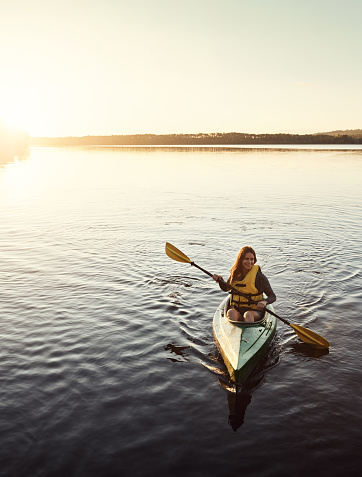 Shot of a beautiful young woman kayaking on a lake outdoors