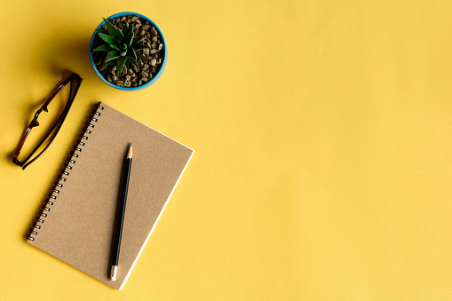 notebook and pencil on yellow desk